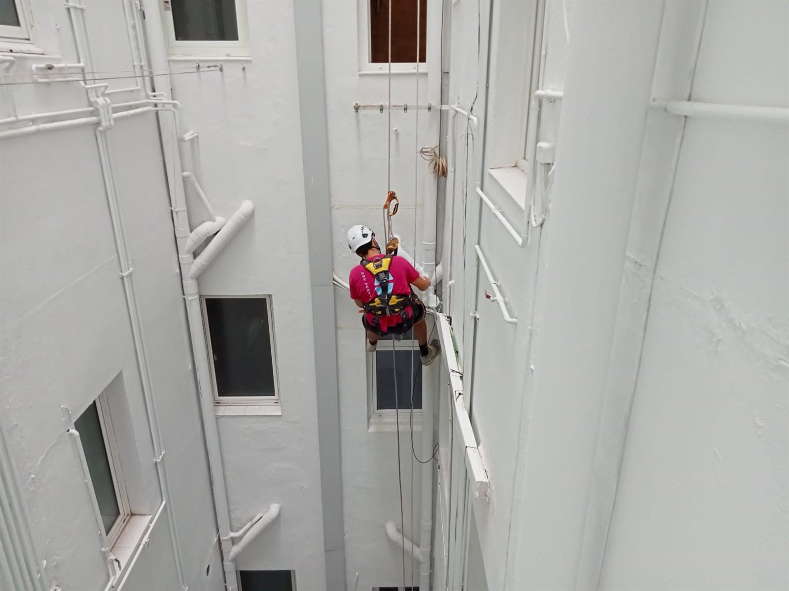 Técnico vertical reparando bajantes en un patio interior de un edificio de Barcelona